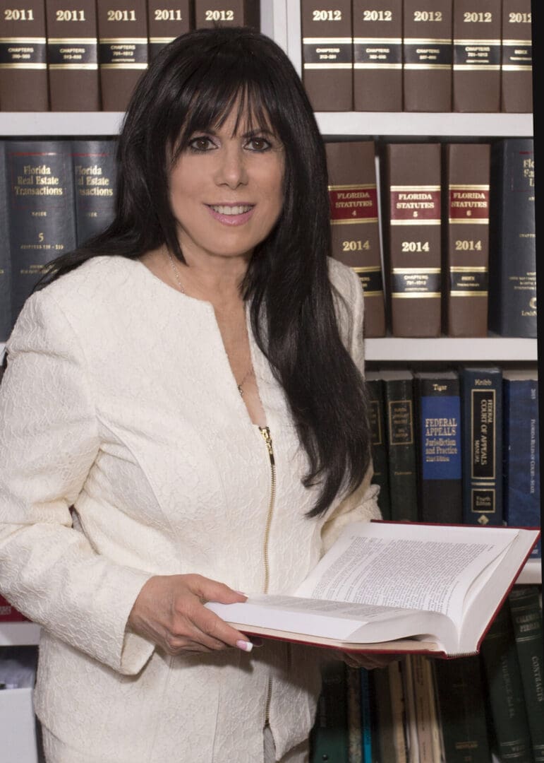 Woman holding book in library setting.